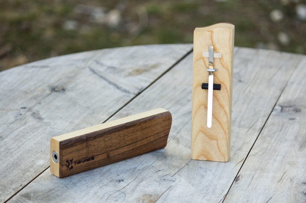 deux pièces en bois une  debout avec une lamelle en métal fixée dessus et l'autre sur le coté posé sur une table en bois